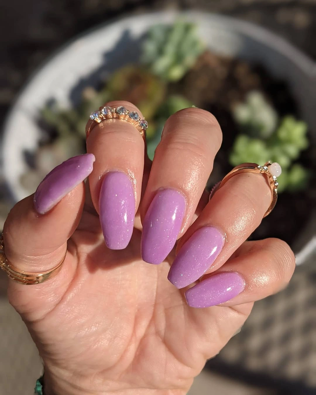 Glossy lavender purple tapered square nails on a hand with rings