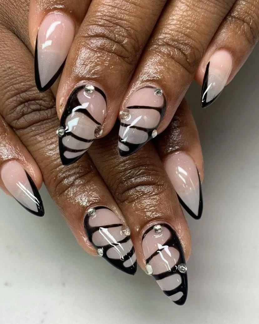 Milky nude almond nails with black graphic swirls and pale wave details