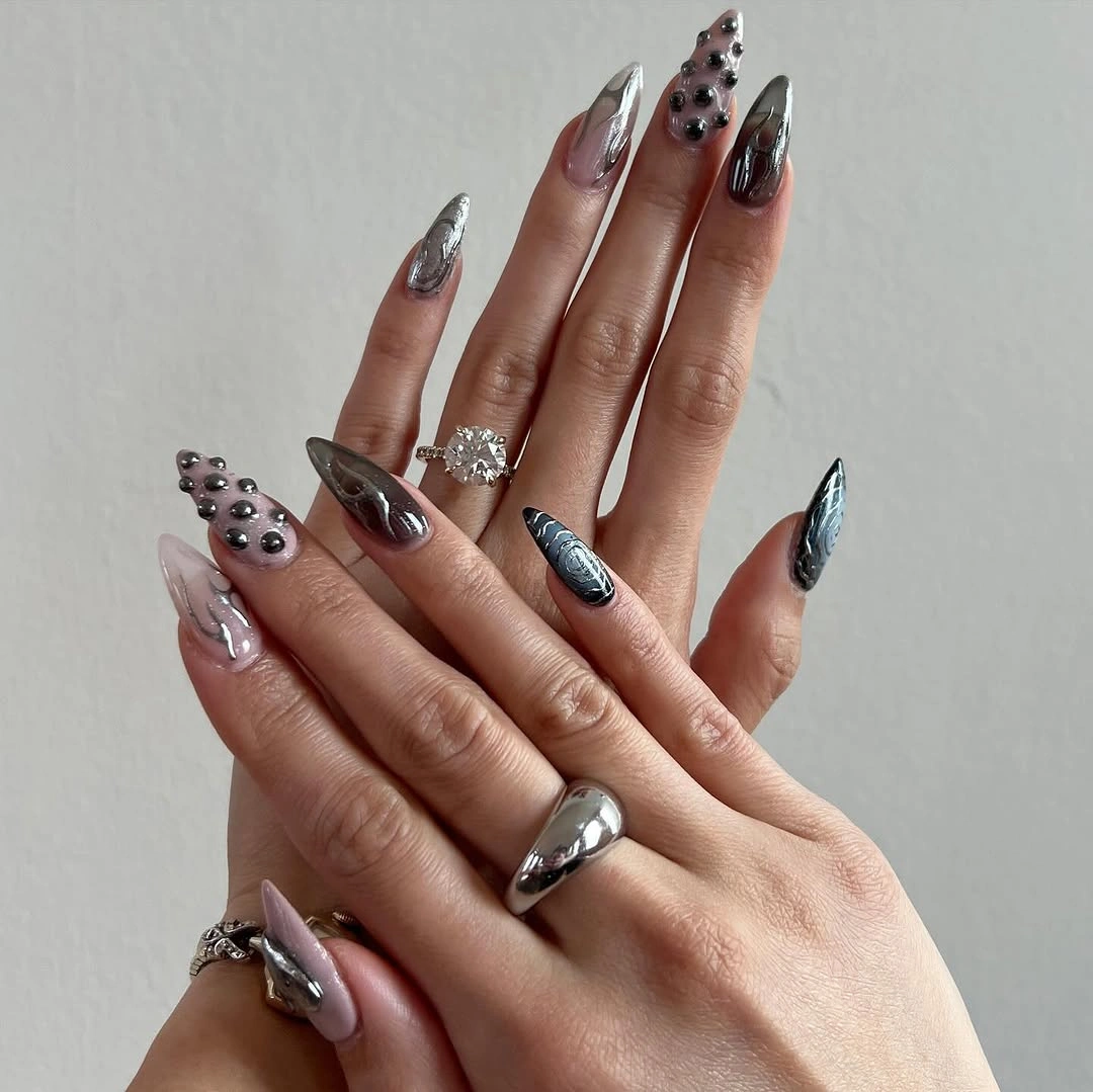 Long pointed smoky silver-gray nails with dark graphic and dimensional accents