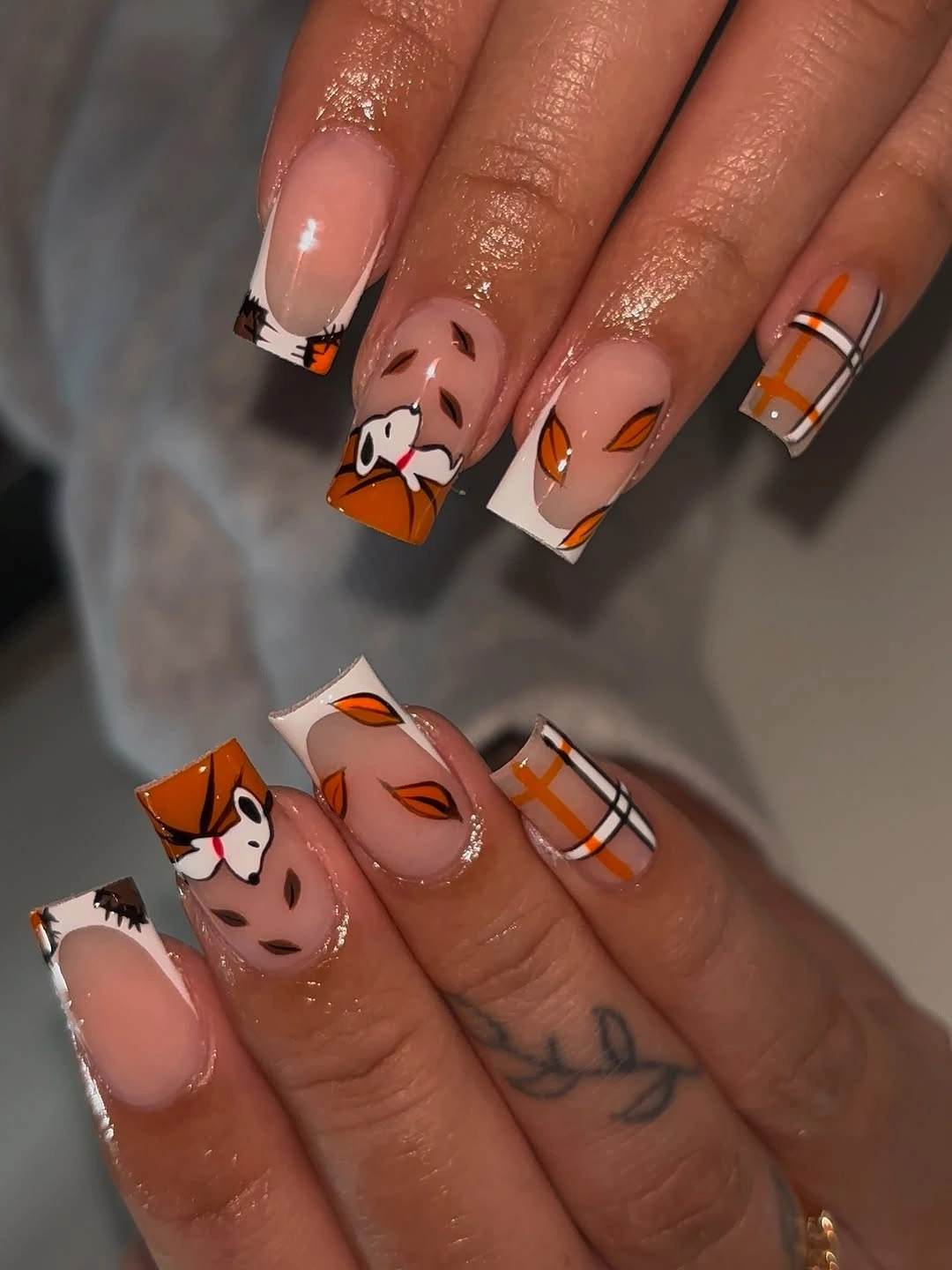 Medium square nails with orange tips and playful autumn marks