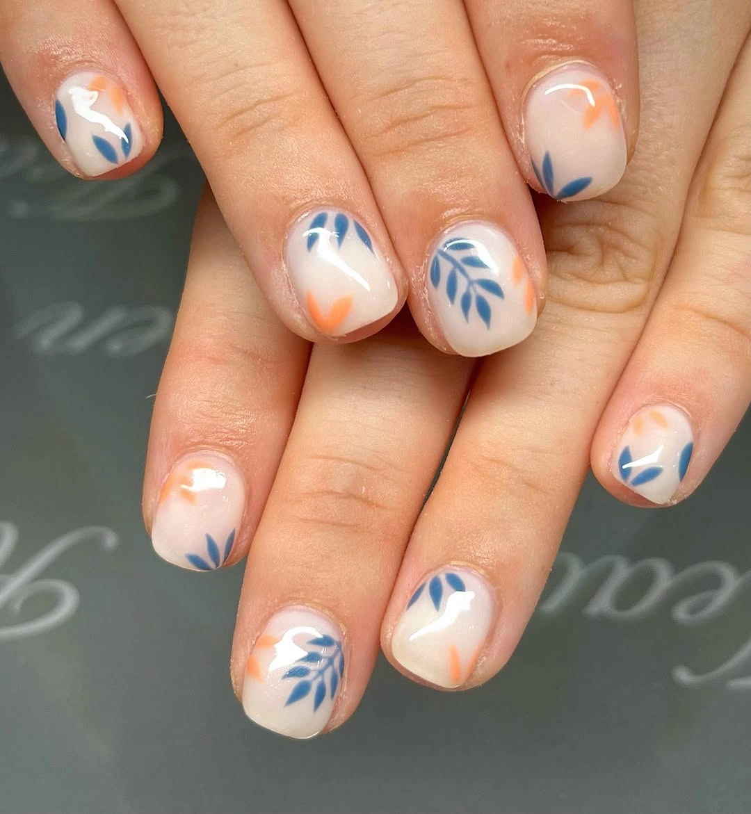 Short milky nails with blue leaves and orange accents