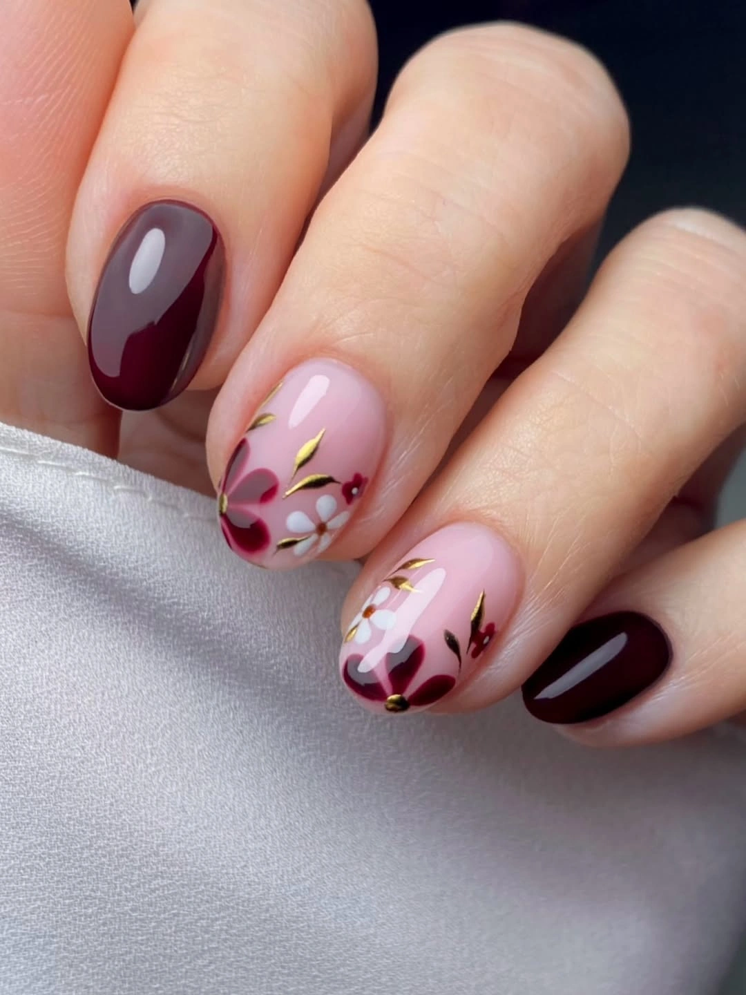 Pink almond nails with burgundy and gold floral leaves
