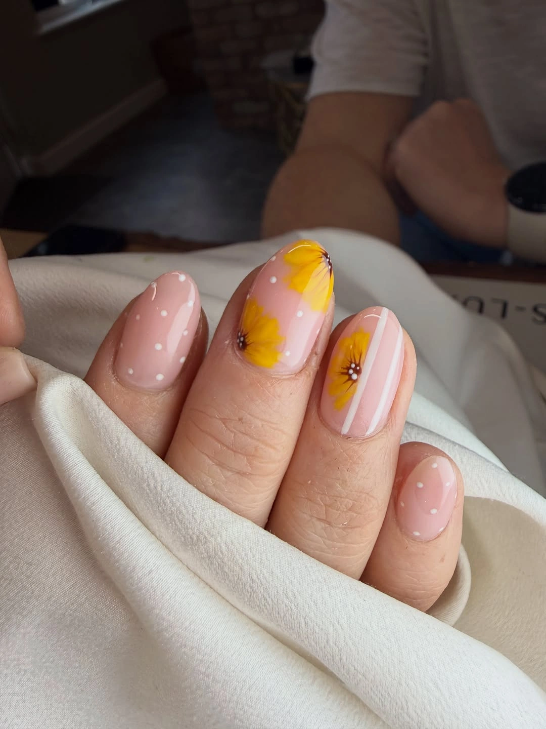 Soft pink almond nails with white dots and yellow flowers