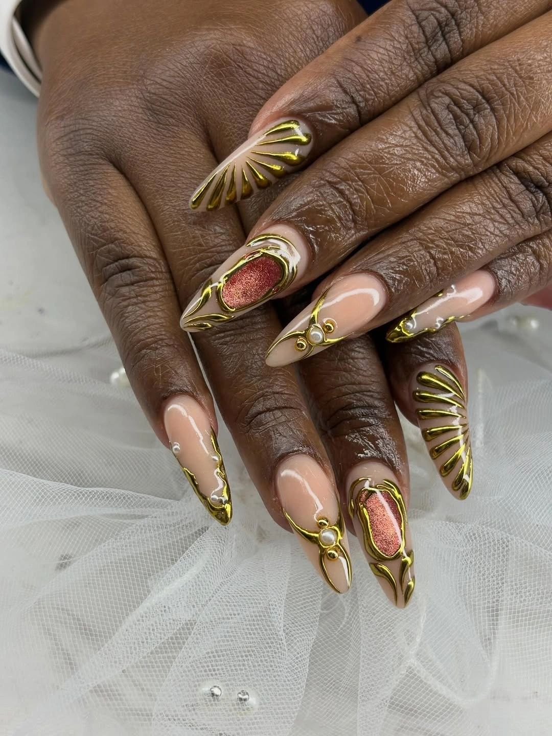 Long burgundy stiletto nails with nude base and ornate gold linework
