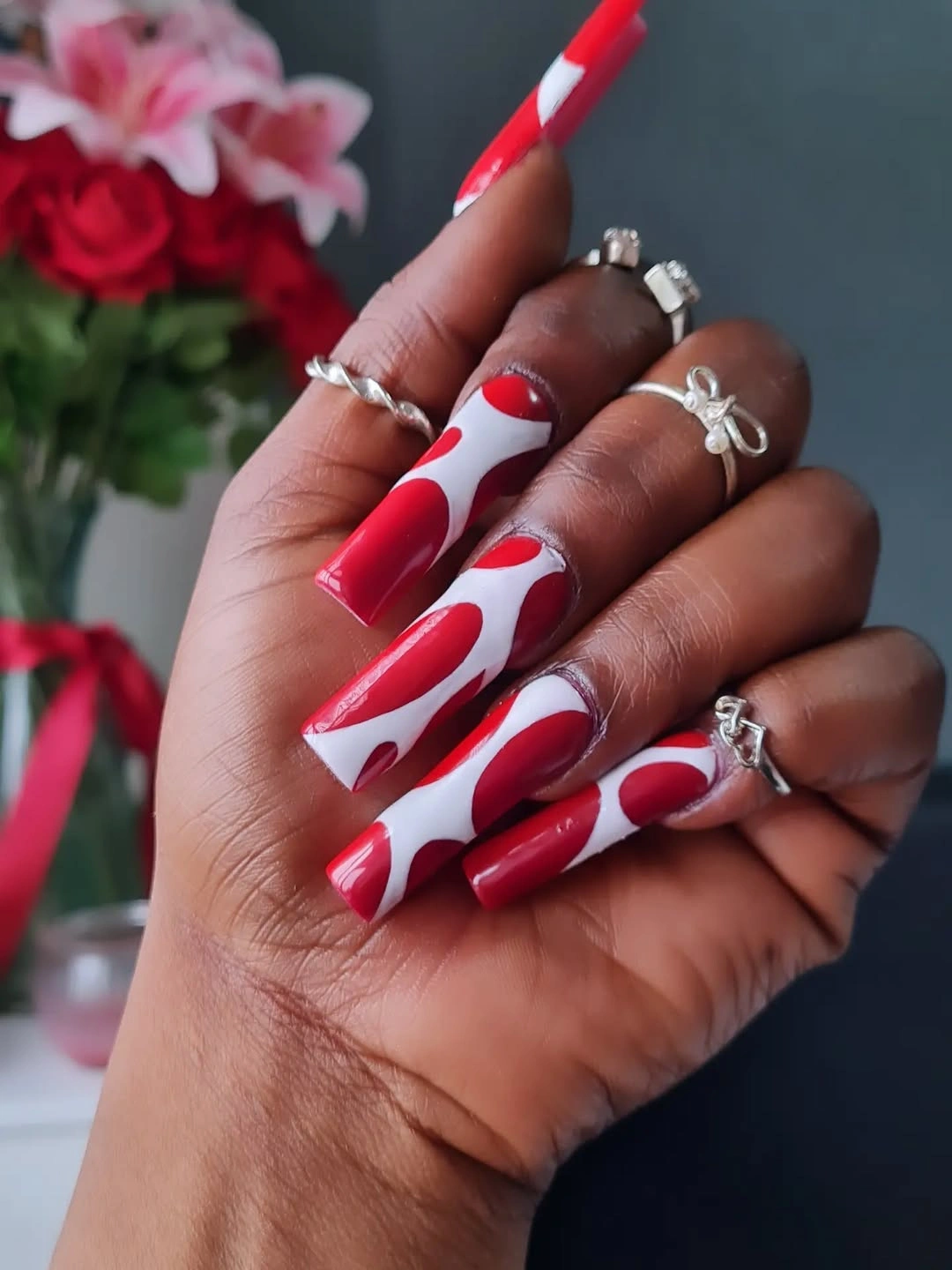 Long red and white curved nails with flowing abstract bands