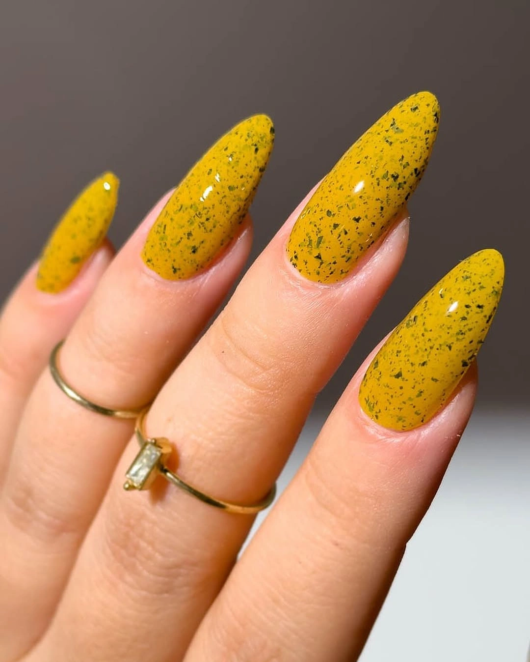 Long almond nails in speckled mustard yellow with glossy highlights