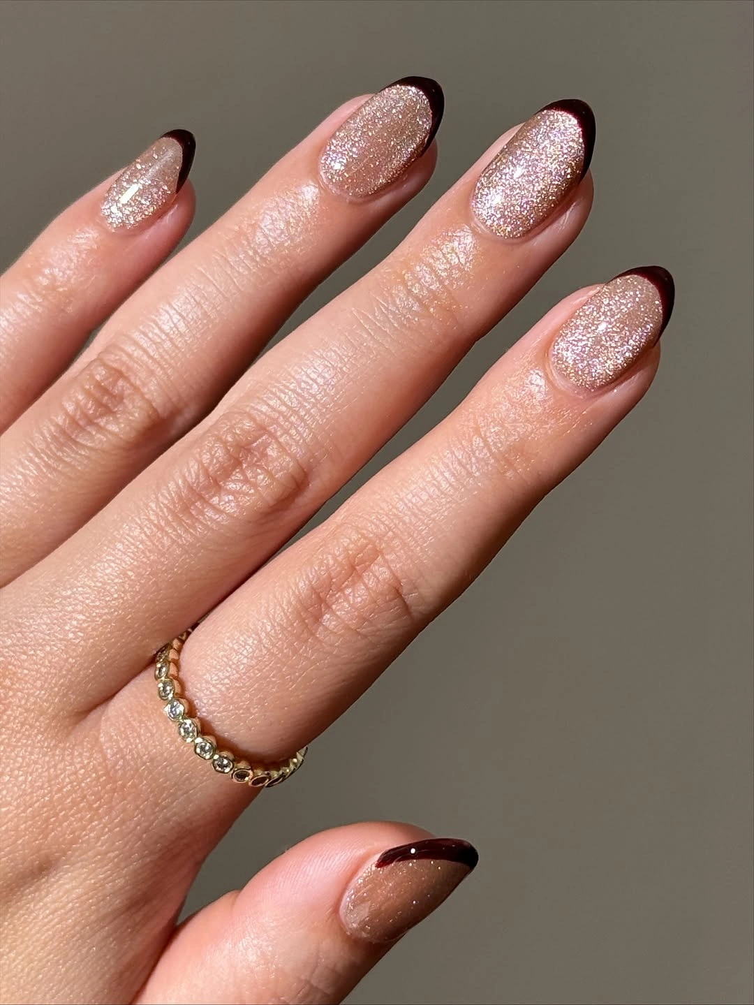 Pale pink glitter almond nails with deep brown French tips