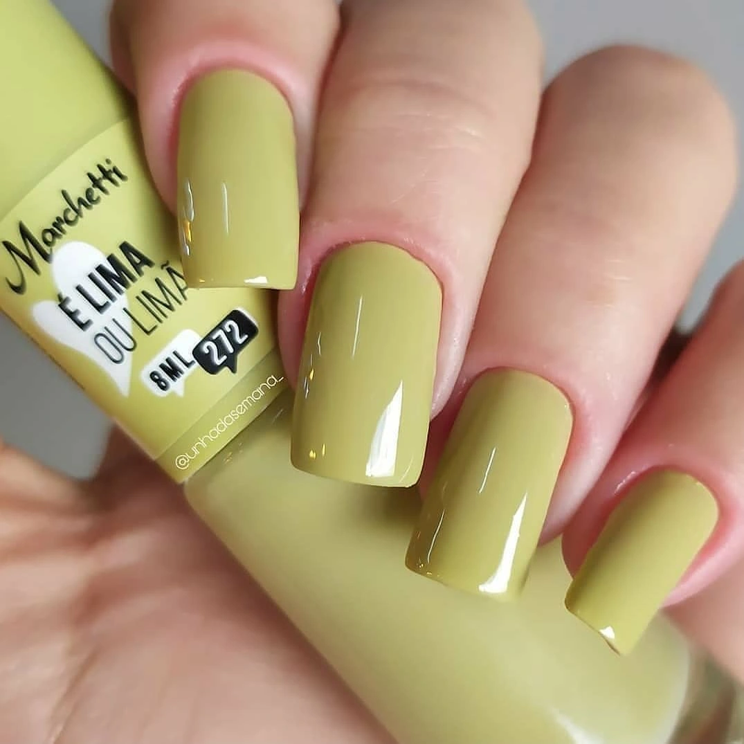 Short square nails in a glossy yellow green manicure color