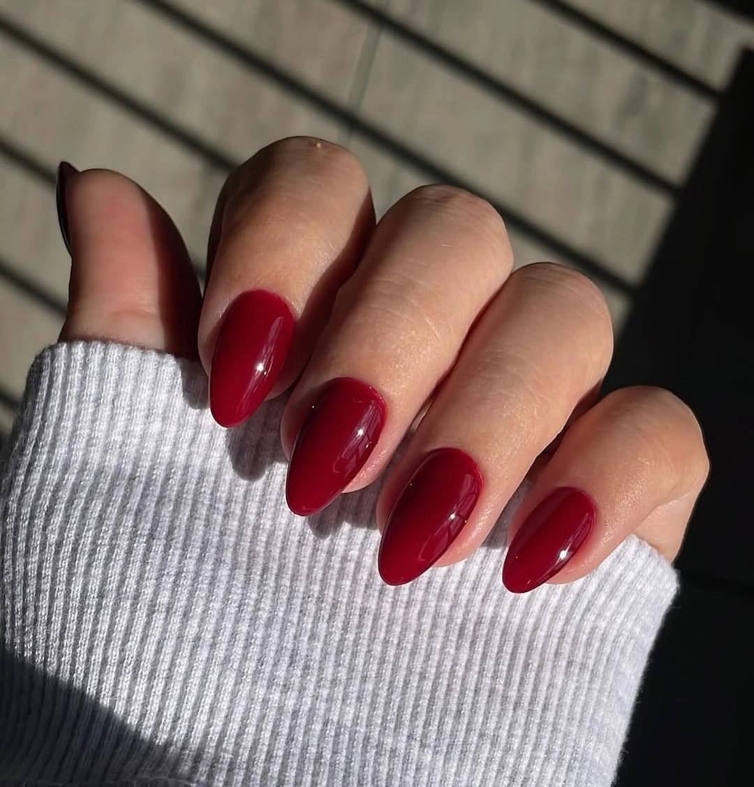 Glossy deep burgundy almond nails with a clean seasonal finish