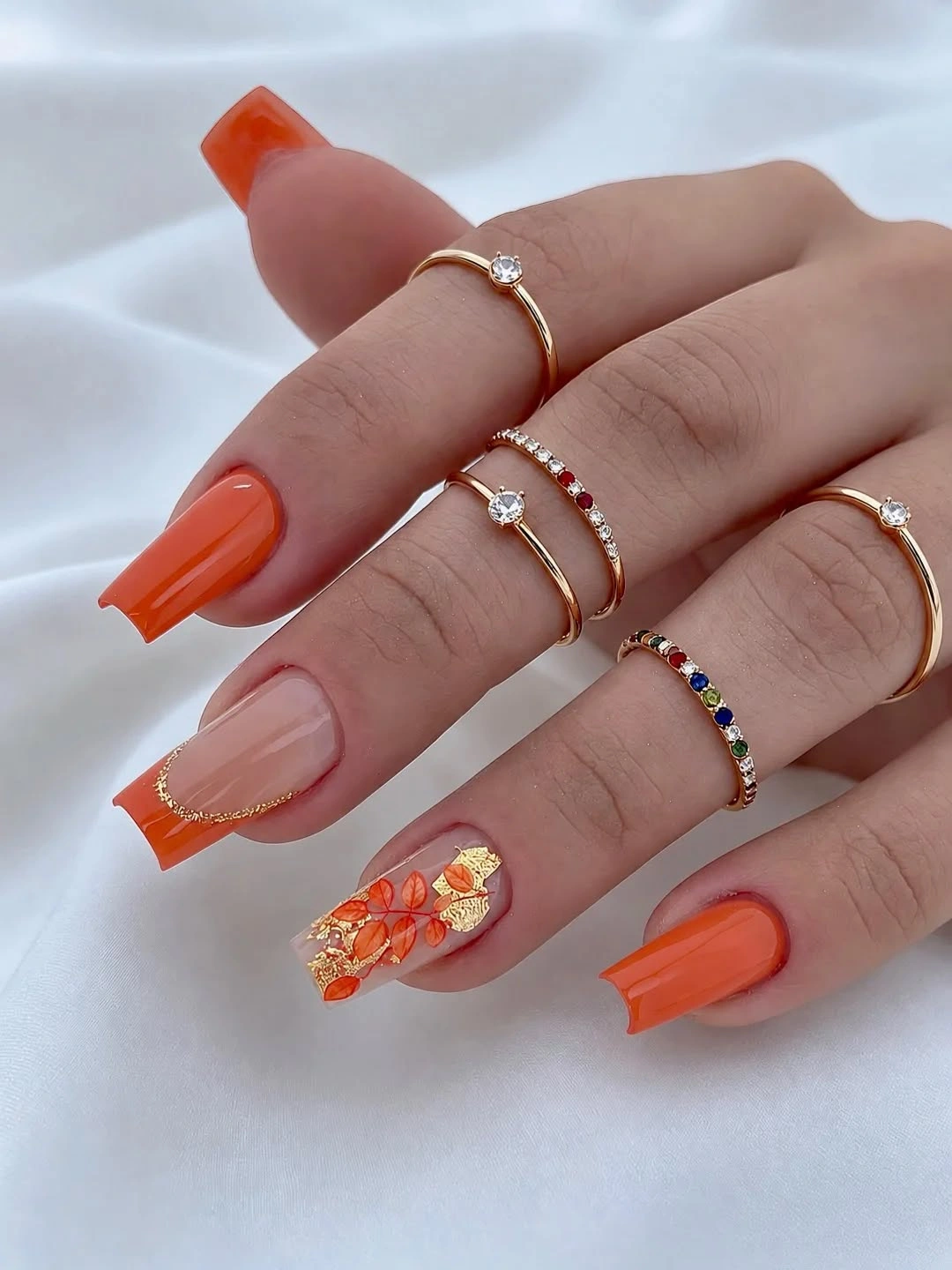 Sheer pink nails with vivid orange tips and warm accent detail