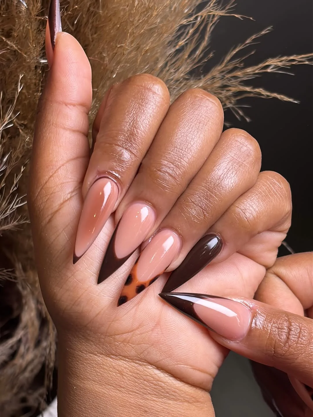 Very long sheer pink nails with dark pointed V tips
