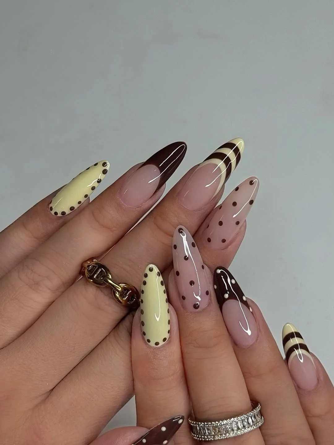 Butter yellow and brown almond nails with curved stripes