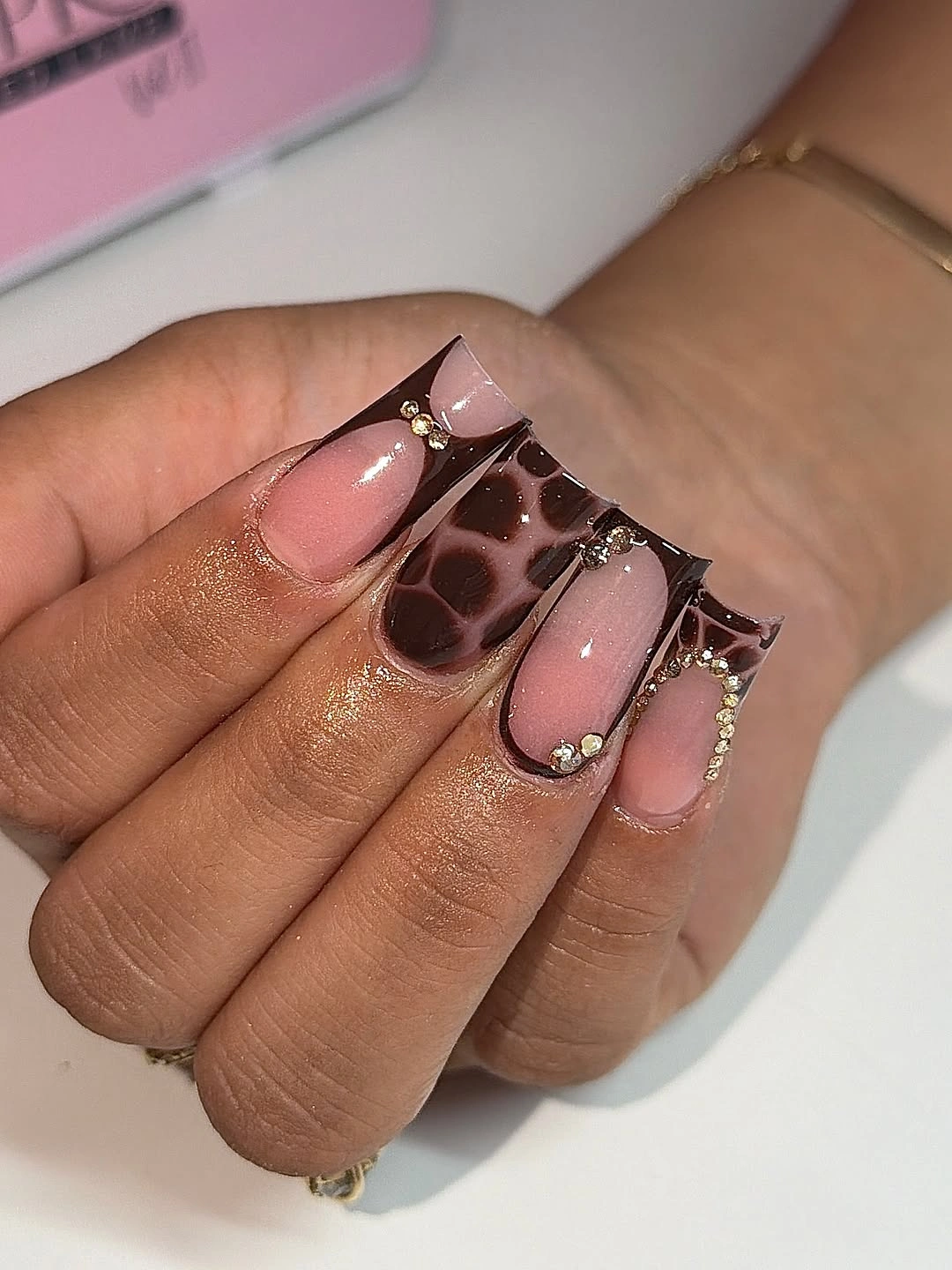 Sheer pink almond nails with rounded chocolate brown loops