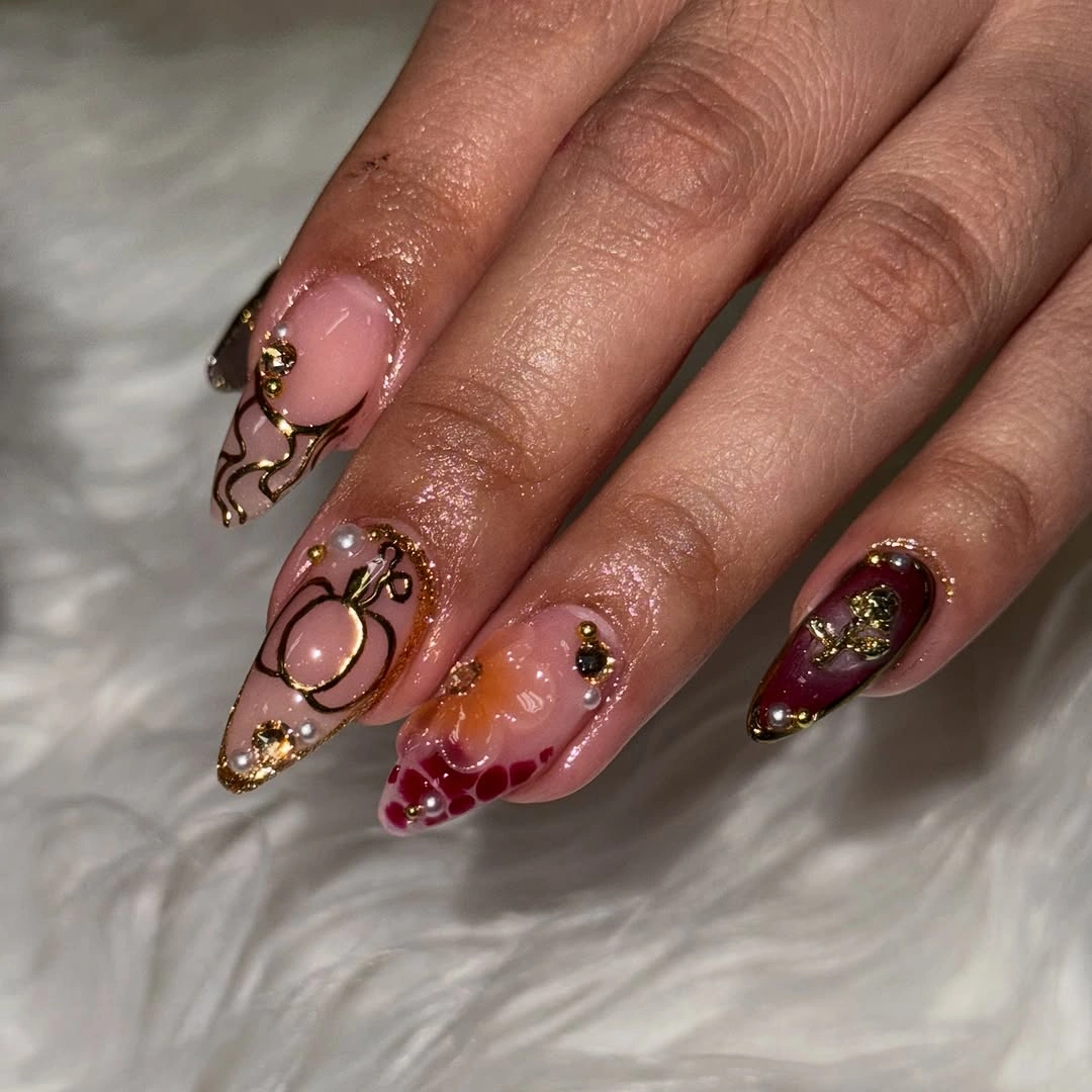 Blush almond nails with burgundy curves and small sparkling accents