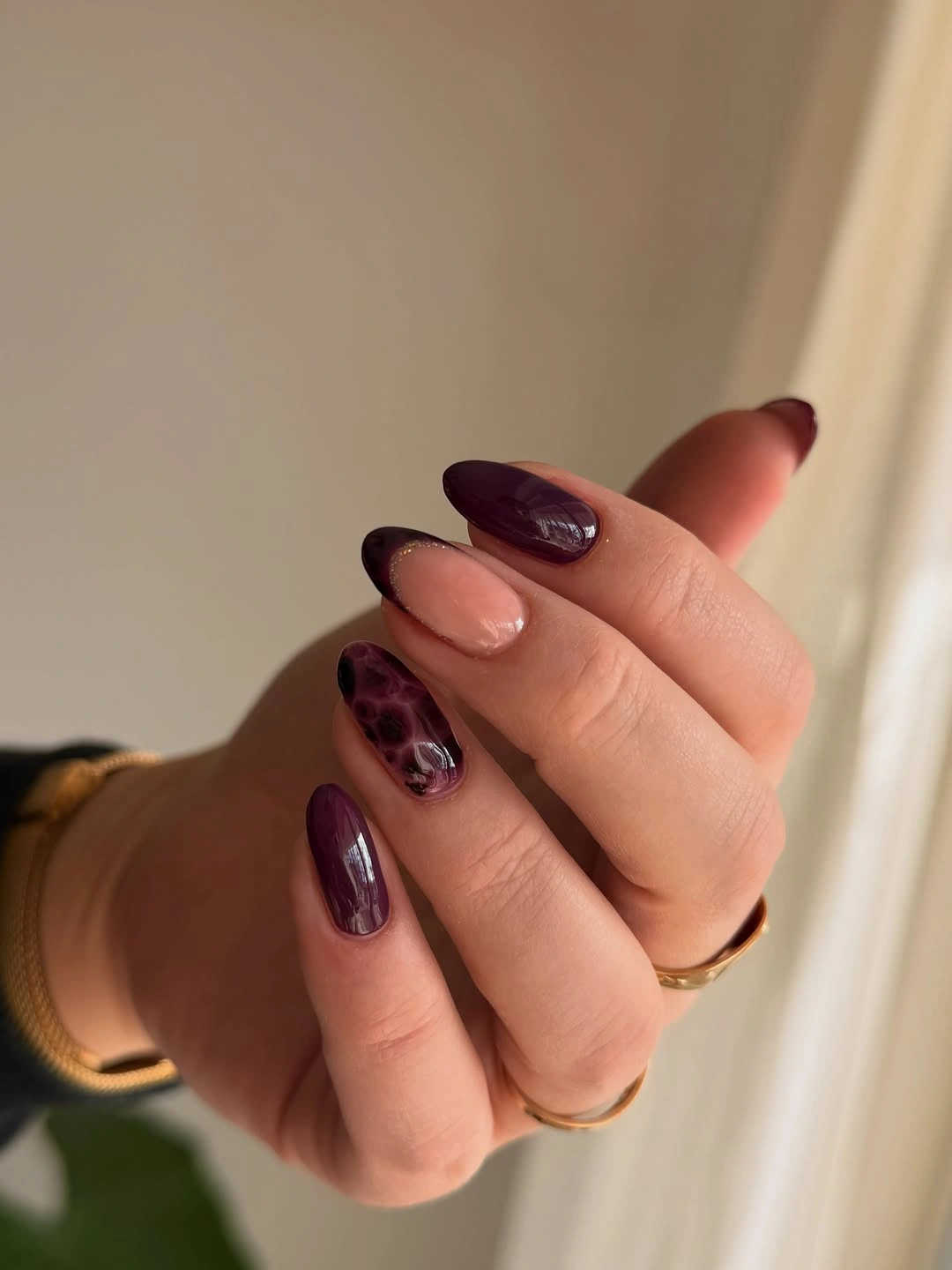 Plum and nude almond nails with one speckled accent