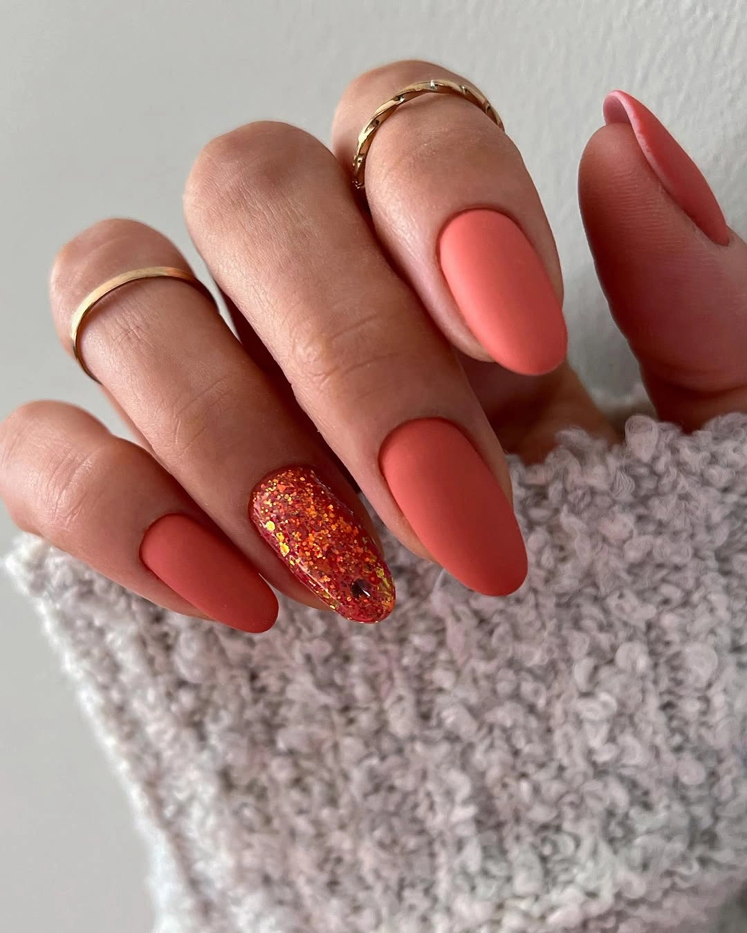 Coral matte nails with one dense orange glitter accent nail