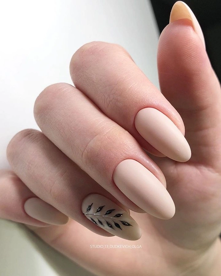 Long pale nude almond nails with one delicate dark botanical accent