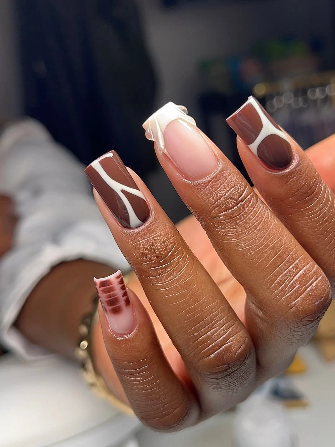 Square nails with brown negative space panels and white outlines
