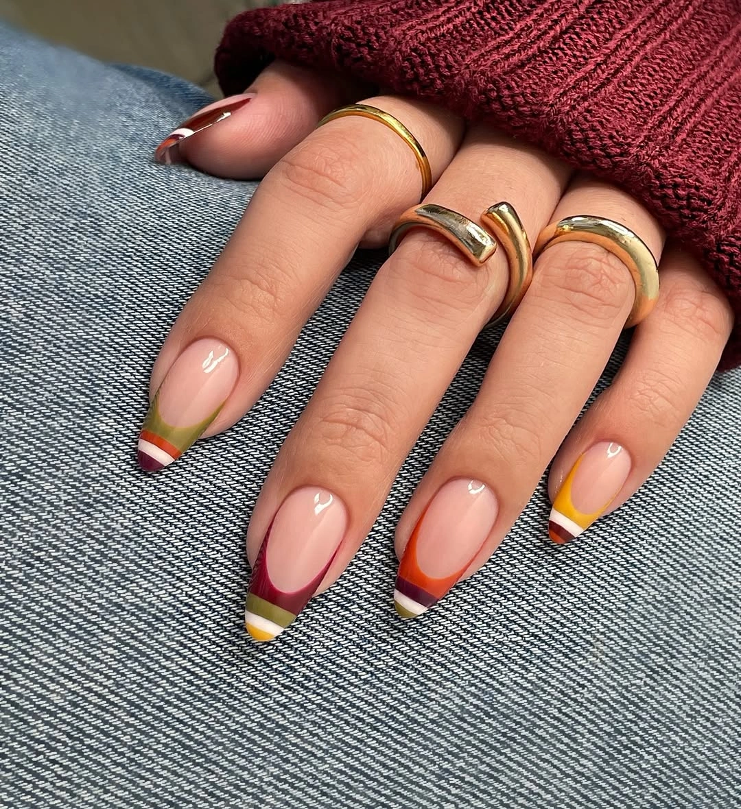 Nude almond nails with slim red yellow and brown tips