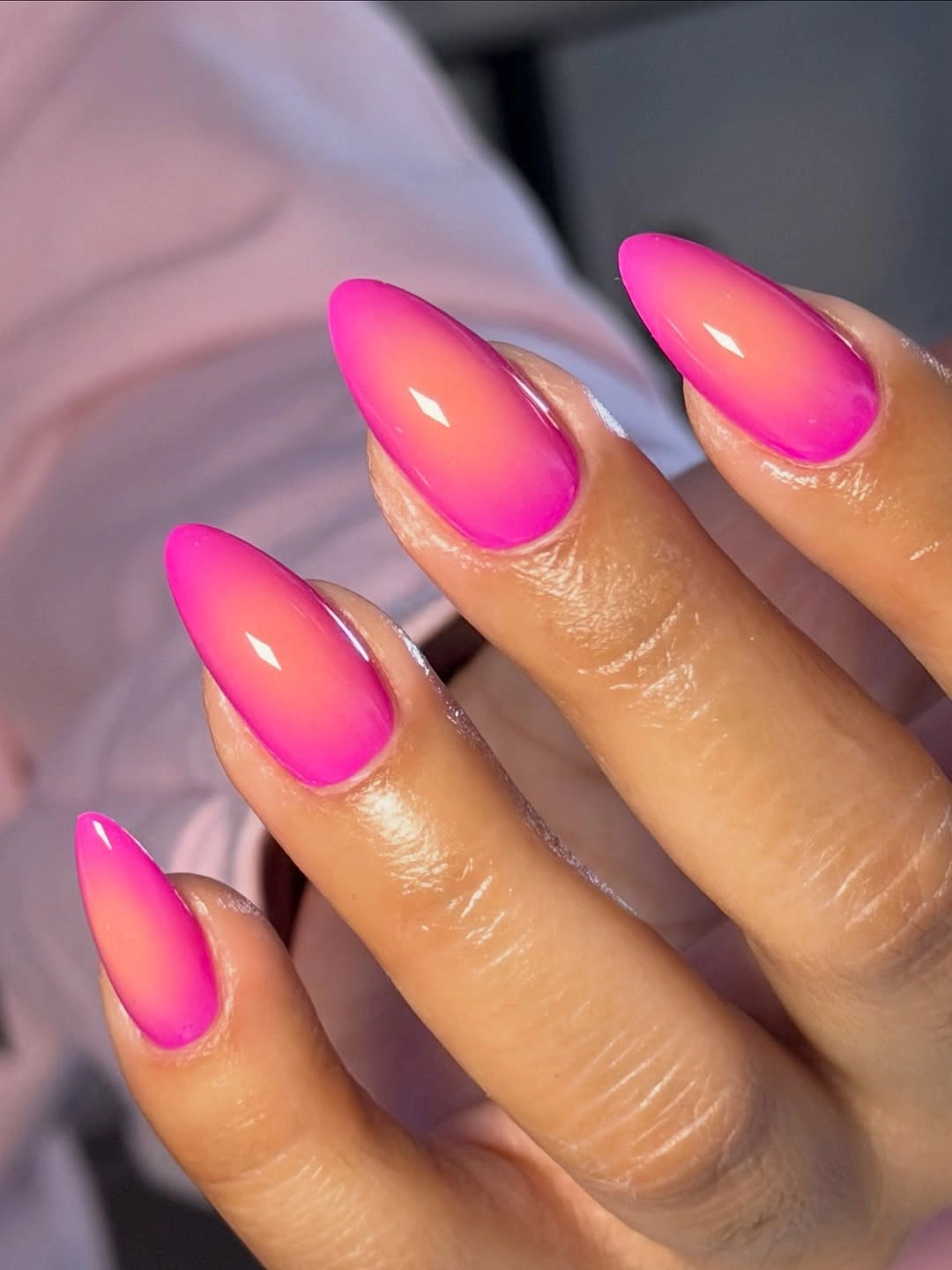 Glossy hot pink almond nails with a bright reflective highlight