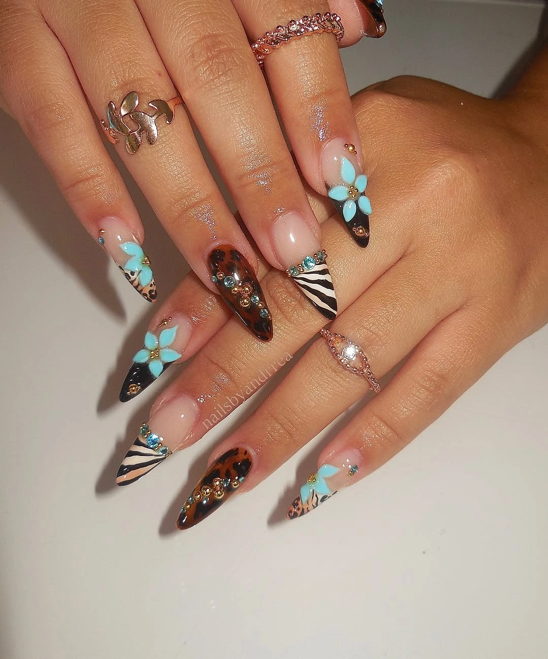 Almond nails with turquoise flowers brown tips and striped accents