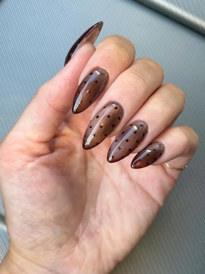 Translucent brown almond nails with a dark tonal dot pattern