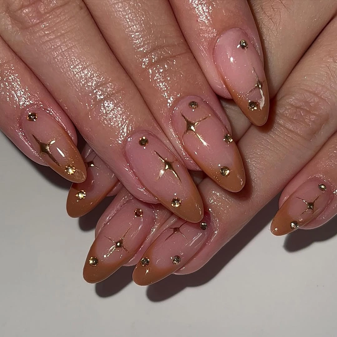Pink almond nails with brown French tips and delicate gold accents