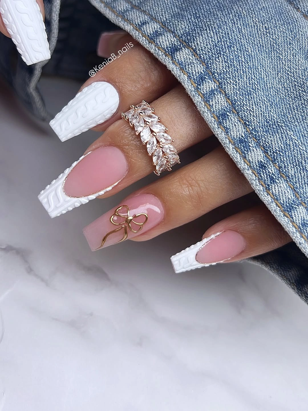 Pink almond nails with white textured French edges and a small bow