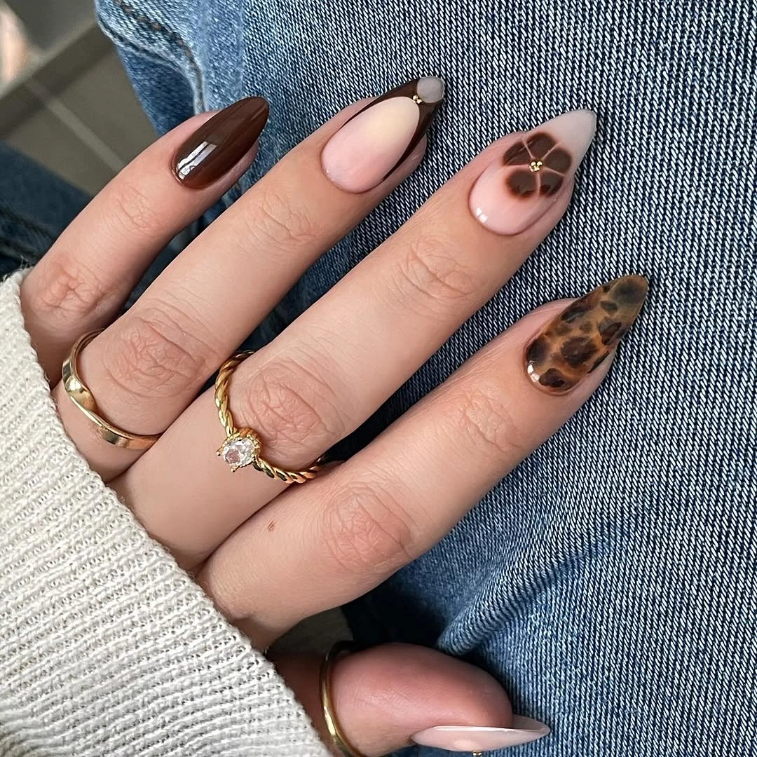 Medium almond nails with dark solids and one warm patterned accent