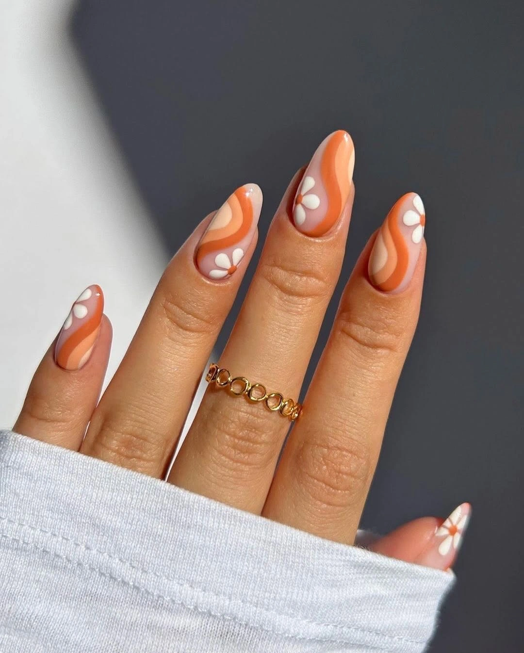 Peach almond nails with white and orange abstract swirls