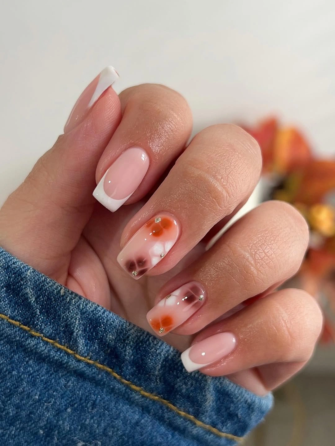 Compact square nails with pale tips and warm accents