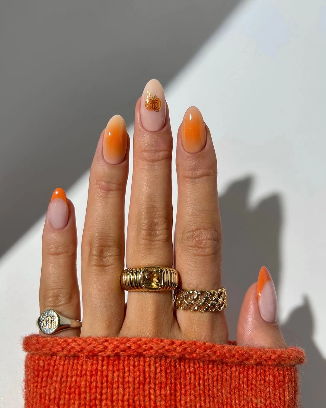 Medium almond nails with bright orange French tips and gold detail