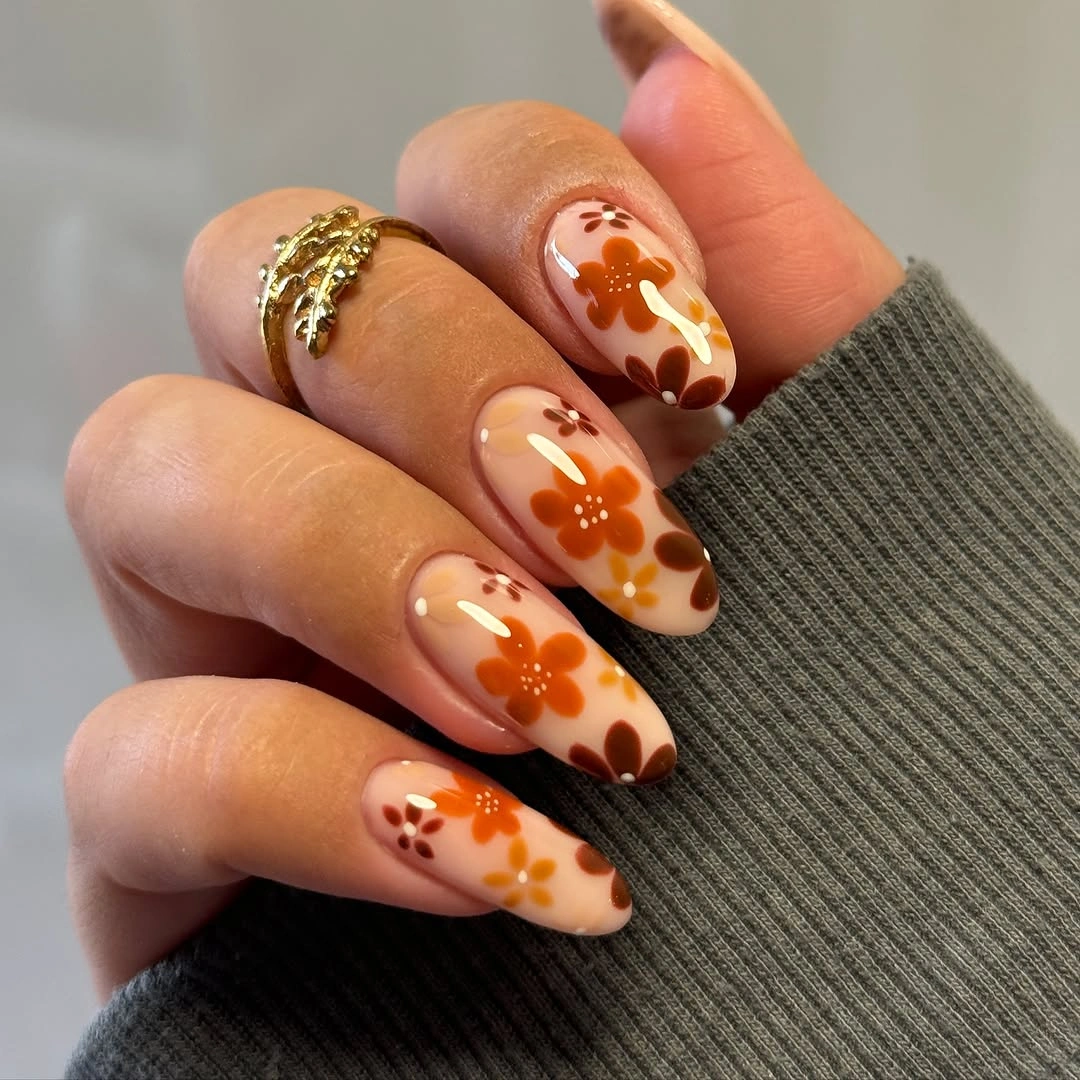 Medium square nails with orange botanical accents on peach bases