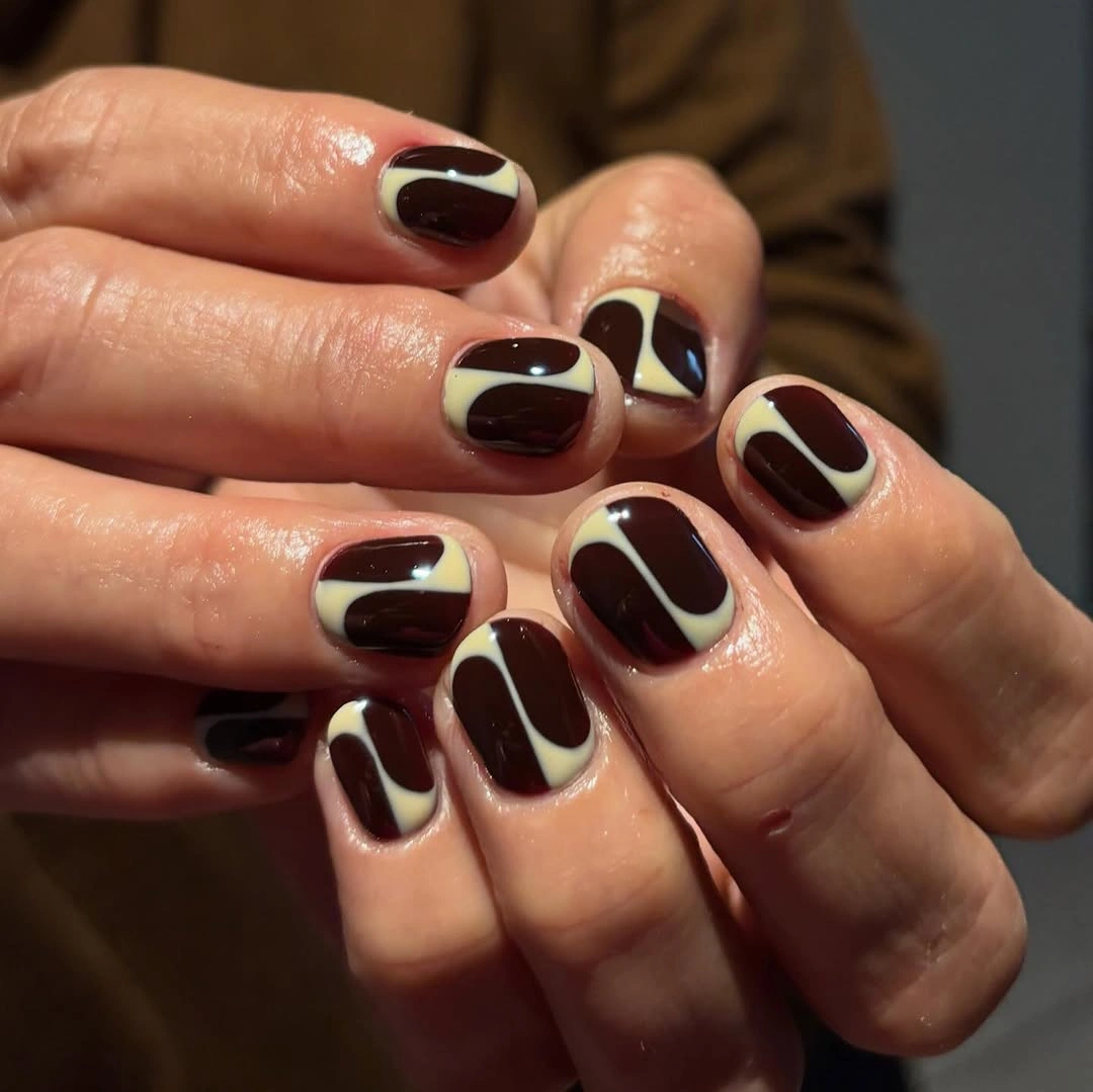 Short rounded burgundy nails with cream geometric panels