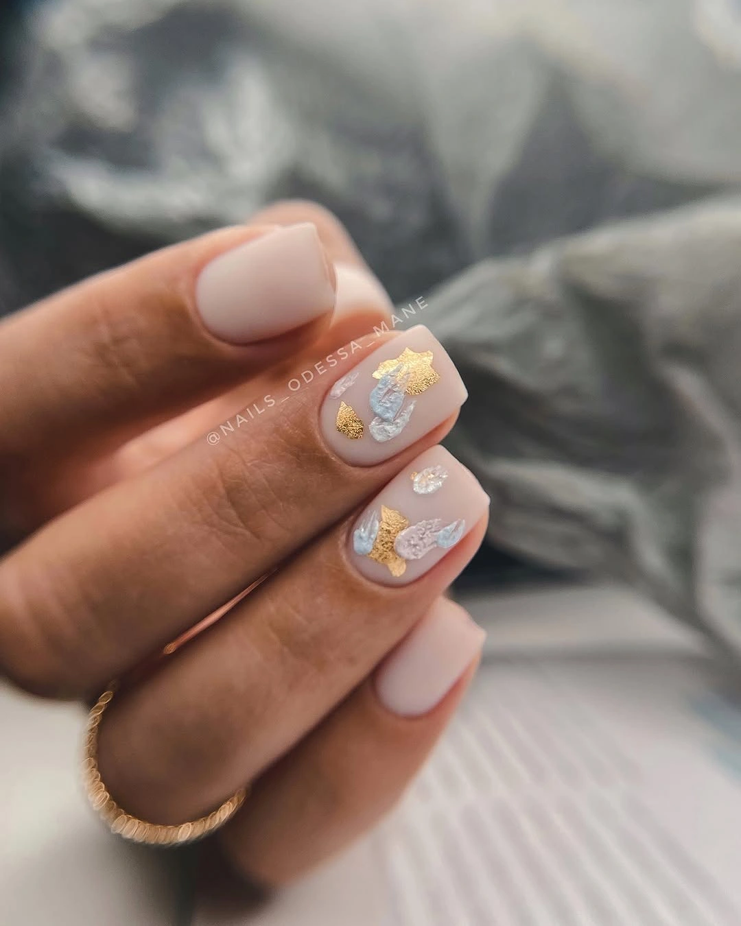 Short rounded pink nails with pale floral and gold accents