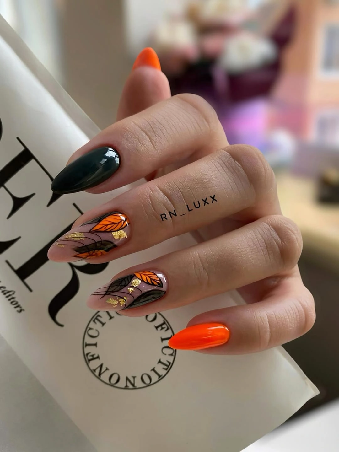 Long stiletto nails with bright orange and deep green accents