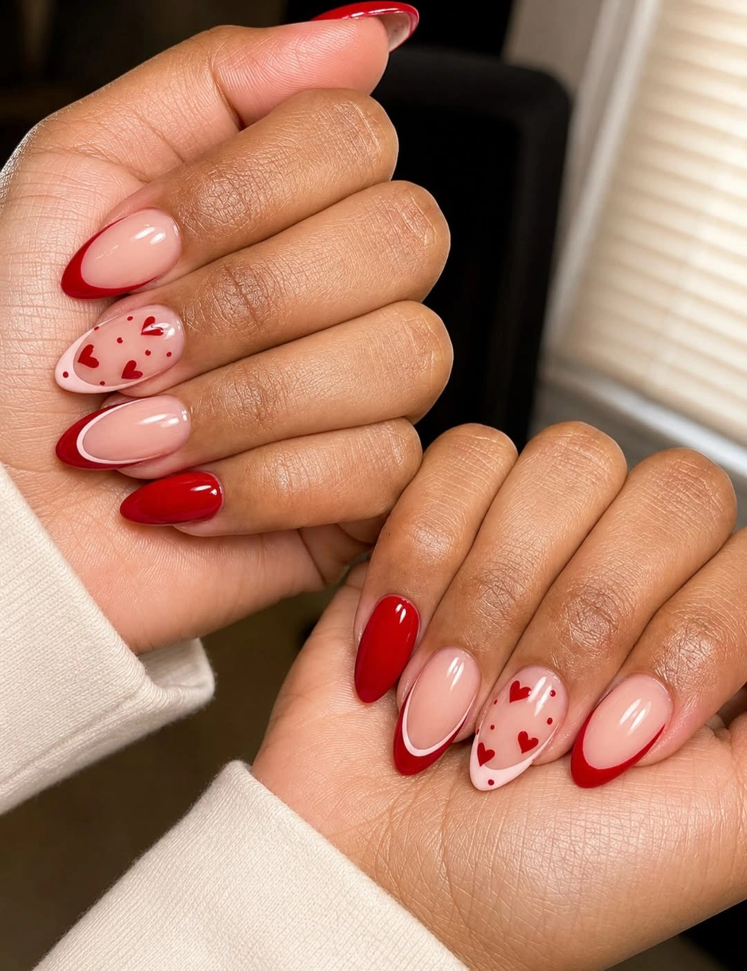Glossy red almond nails with cream heart accents