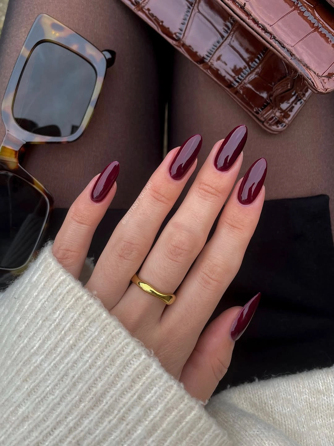 Long almond nails in deep plum with one pale curved accent
