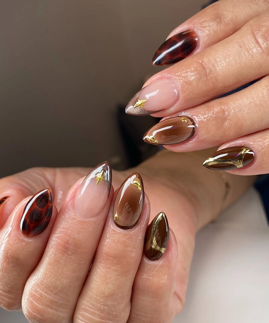 Long almond nails with metallic burgundy and brown curved tips