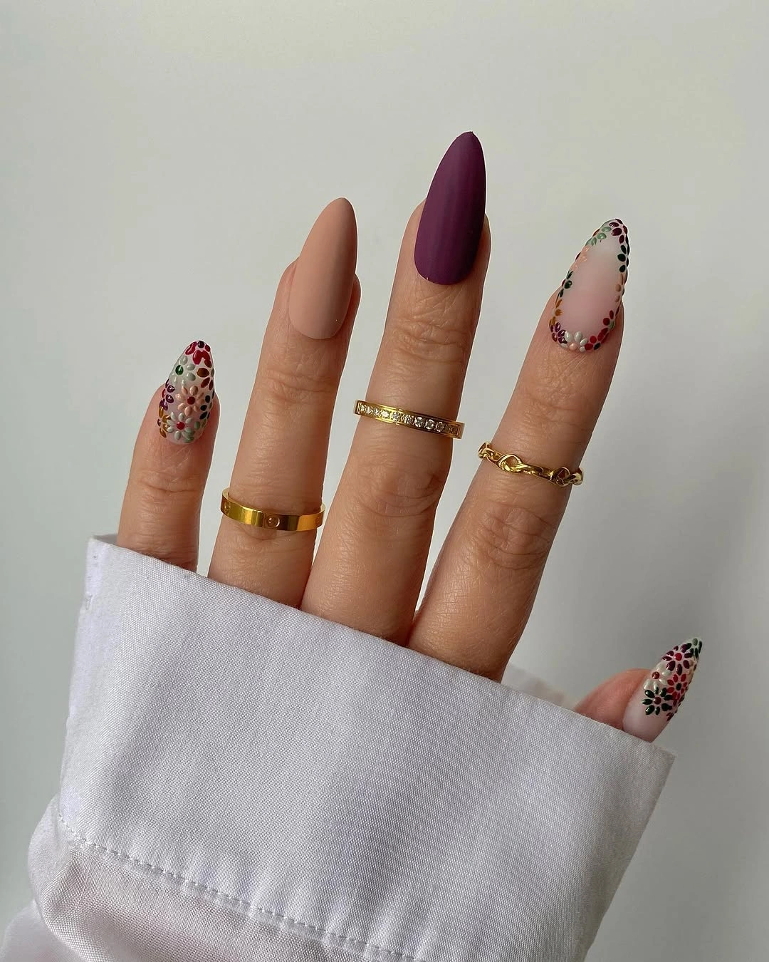 Long almond nails with one plum accent and scattered tip details