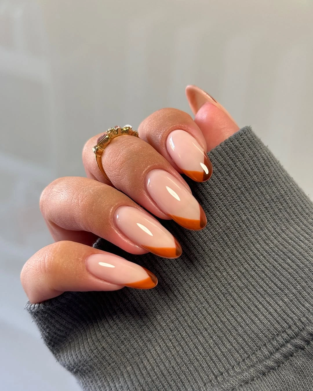 Nude almond nails with warm amber brown French tips
