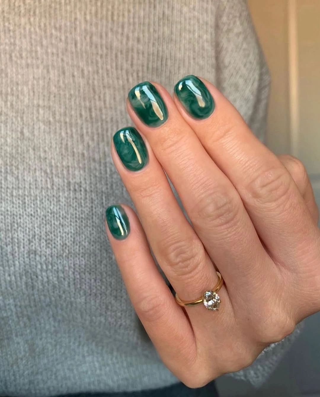 Short glossy emerald nails with subtle marbled depth