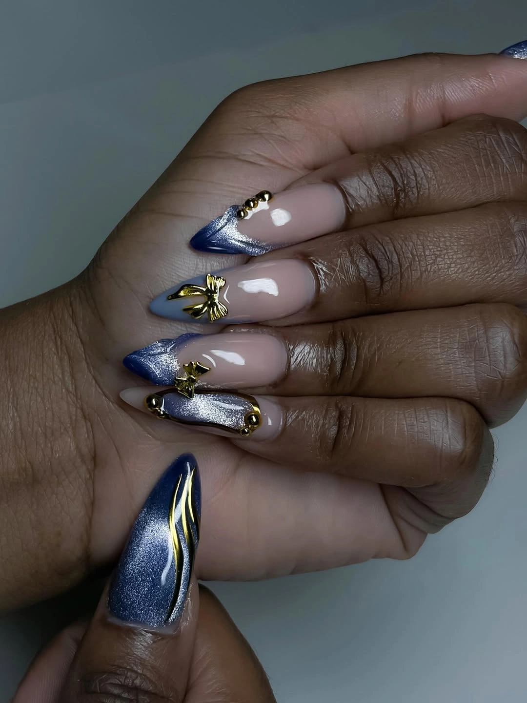 Long pointed nails with blue violet strokes and small gold accents