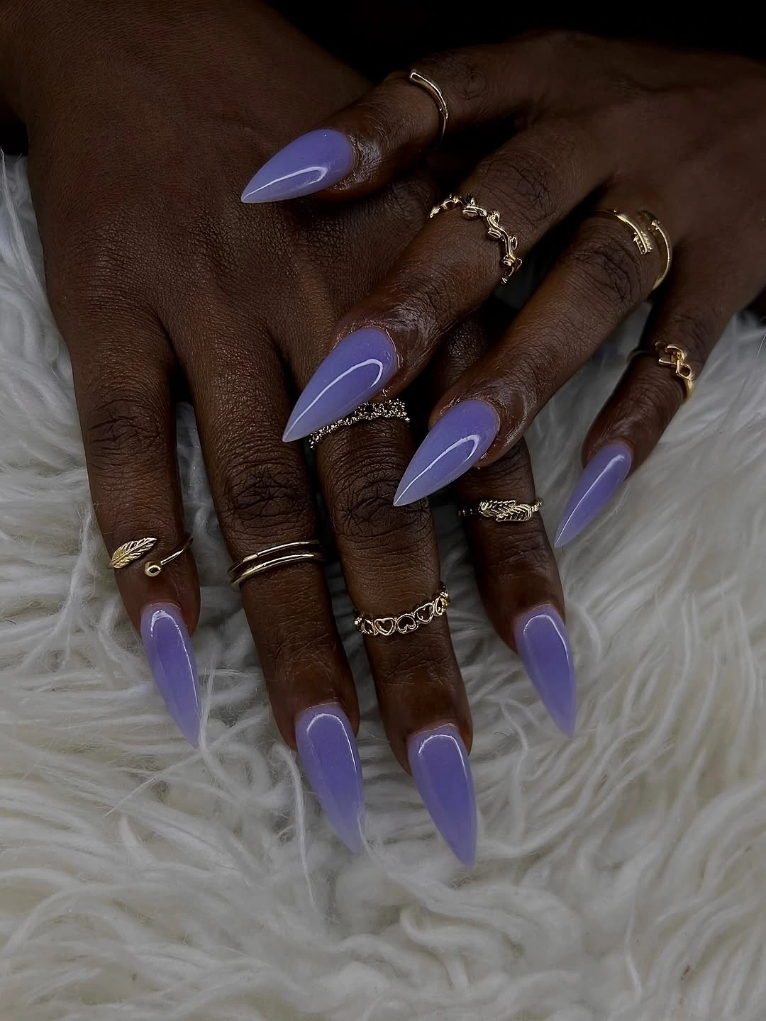 Glossy lavender stiletto nails on deep skin