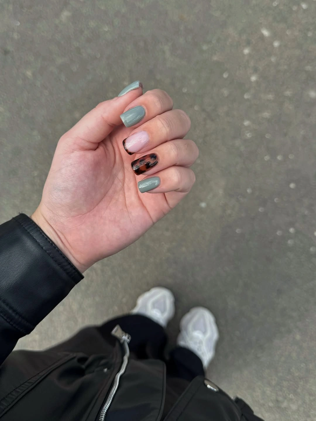 Short square gray-blue and pale pink nails with one dark patterned accent