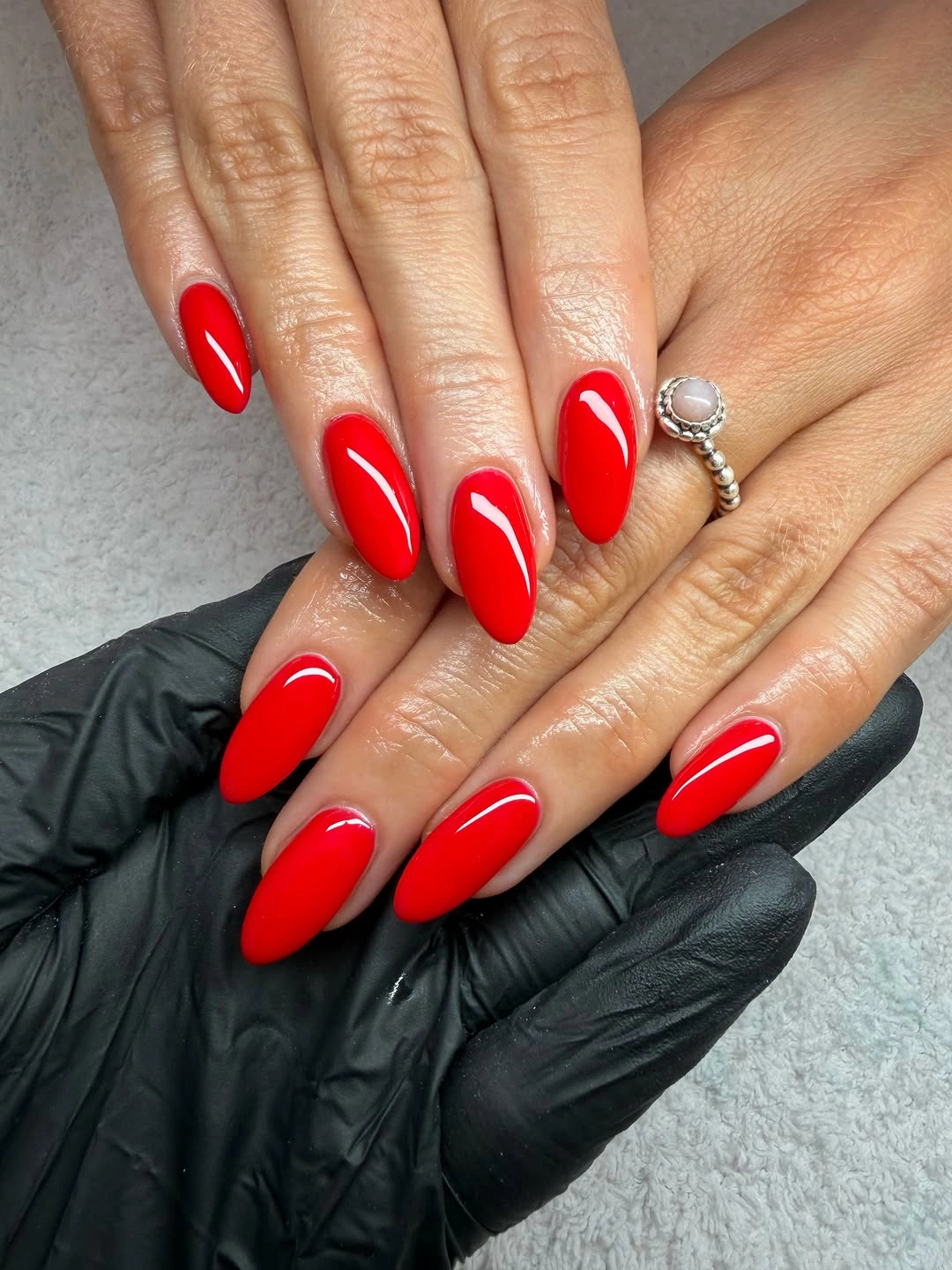 Long almond nails in a uniform glossy true bright red color