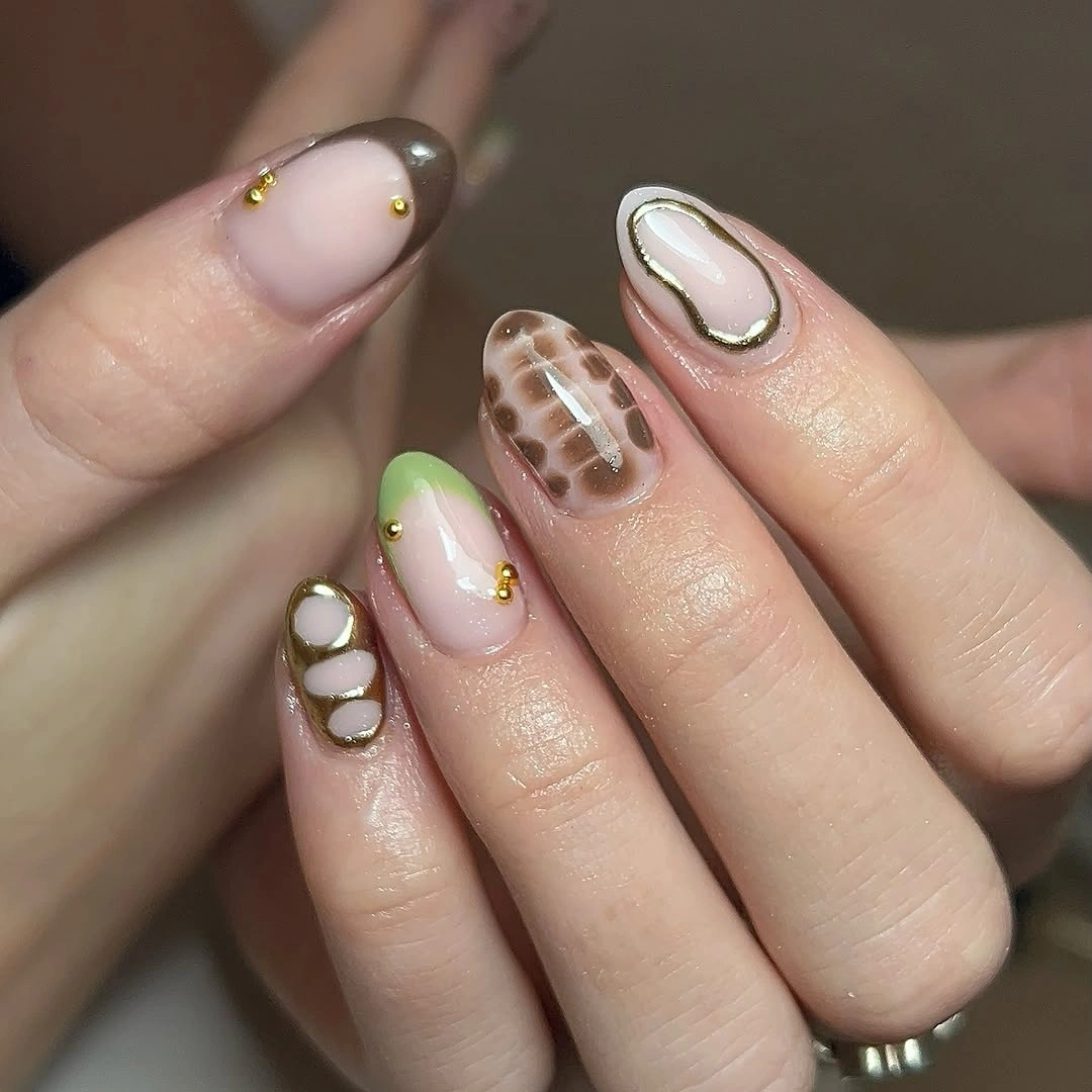 Nude nails with olive green curved tips gold dots and mixed accent details