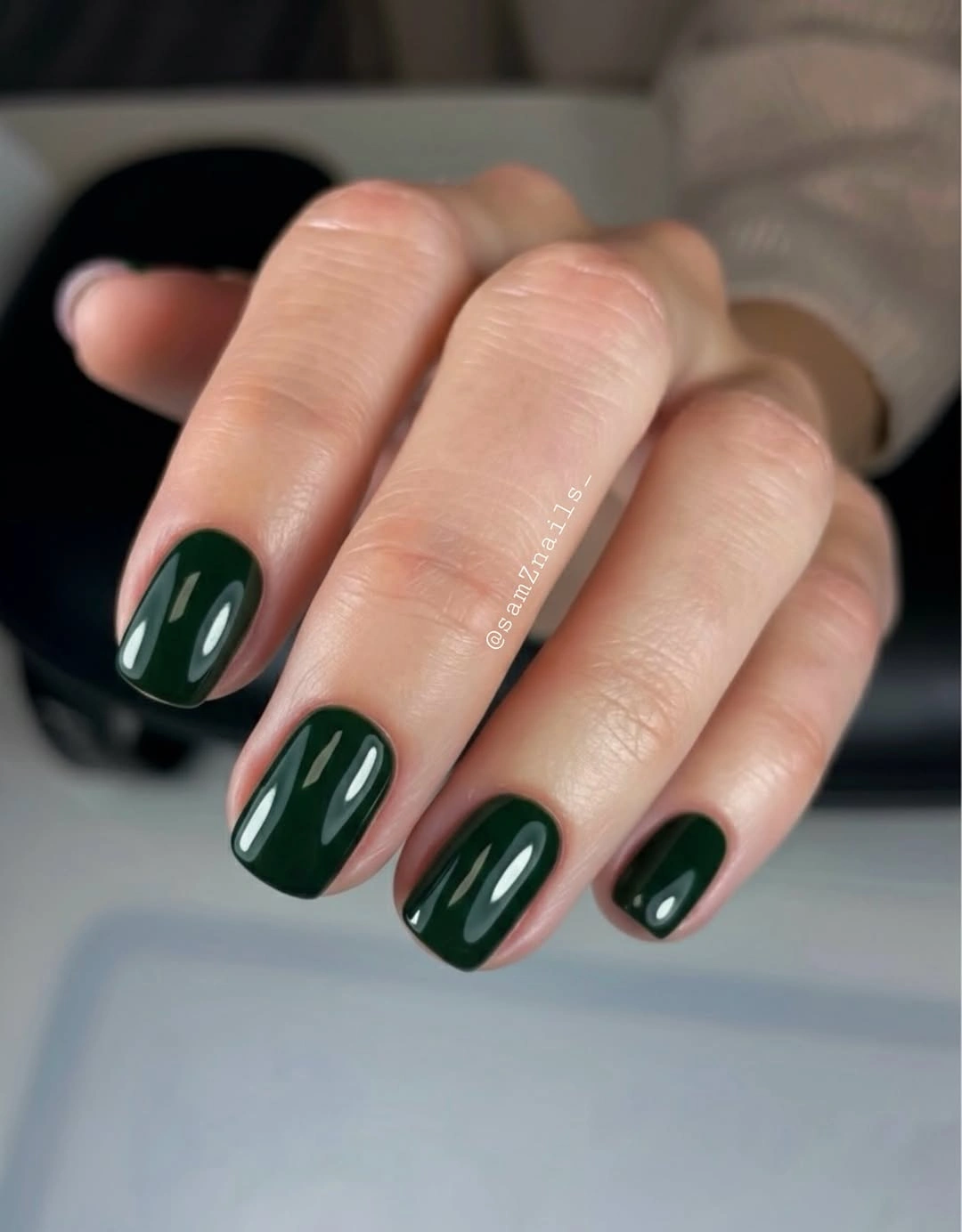 Medium almond nails in a glossy near-black deep green shade