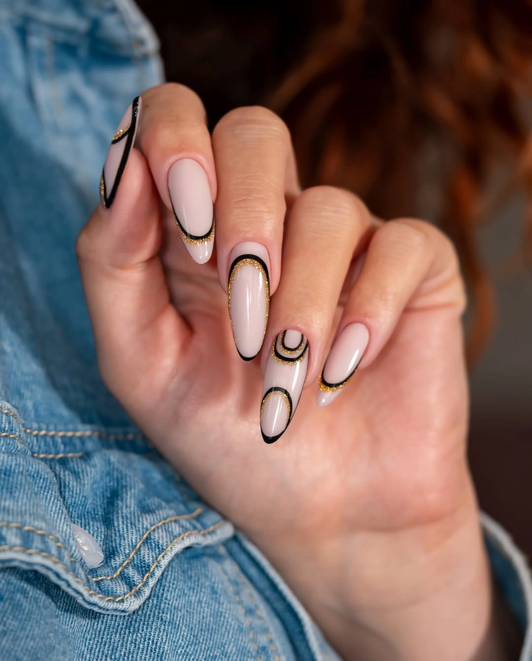 Pale pink almond nails with black and gold double French outlines