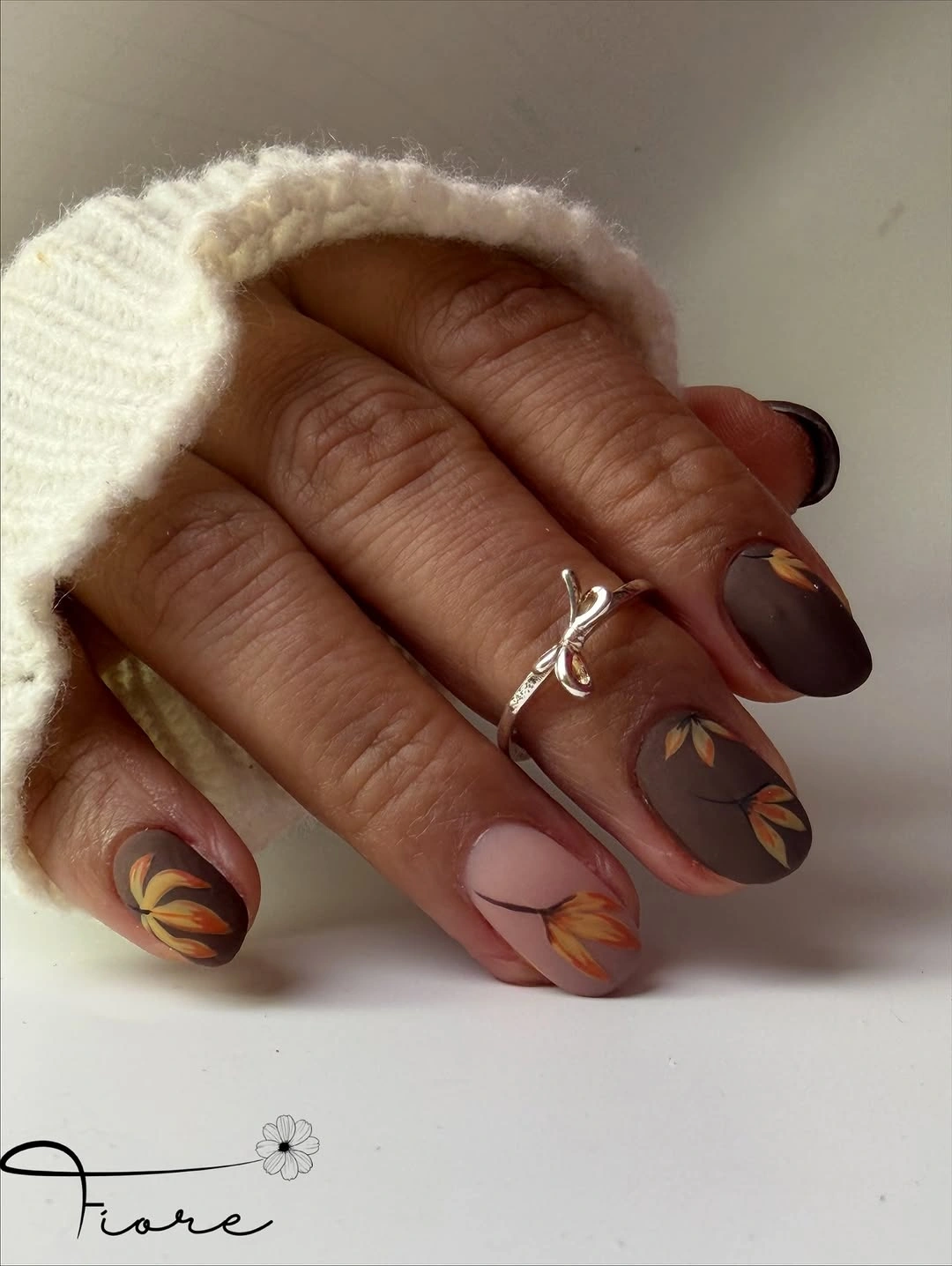 Short brown matte nails with orange botanical marks and pink accent